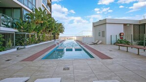 Ein Pool auf dem Dach mit freiem Blick auf die Skyline, umgeben von modernen Gebäuden und üppigem Grün.