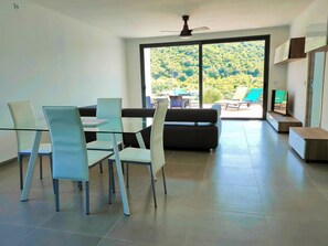 A modern living room with a glass dining table, two sofas, and a ceiling fan. - Charming 2-bedroom villa in São Bartolomeu de Messines with AC and private pool (São Bartolomeu de Messines)