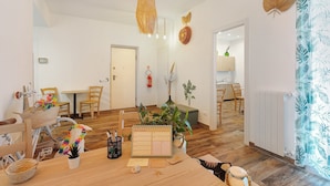 A room with a wooden floor, a table with a calendar, chairs, a bicycle, and a plant. - Room 'Green Roof Palermo - 3 Rosmarino' with Balcony, Wi-Fi and Air Conditioning (Palermo)