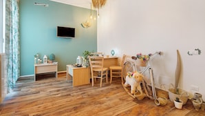A room with a wooden floor, a desk with chairs, a television mounted on the wall, and a hanging light fixture. - Room 'Green Roof Palermo - 3 Rosmarino' with Balcony, Wi-Fi and Air Conditioning (Palermo)