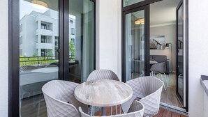 A balcony with a table and chairs, a view of a building, and a door leading to an interior space. - 4 Star Holiday Home in Travemunde (Lübeck)