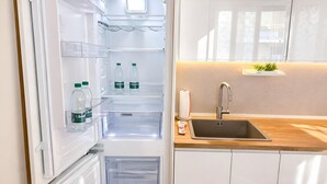 Uma cozinha moderna com geladeira embutida, bancada de madeira e pia de aço inoxidável.