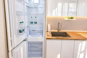Una cucina moderna con frigorifero integrato, un piano di lavoro in legno e un lavello in acciaio inossidabile.