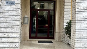 Fachada de mármore, placa com número e porta de vidro na entrada do edifício.