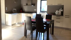 Eine moderne Küche mit weißen Schränken, einer Edelstahl-Dunstabzugshaube und einem Essbereich mit Tisch und Stühlen.