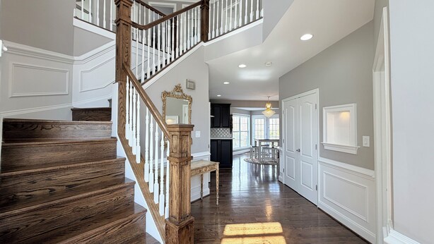 A grand staircase with wooden steps and white balusters, leading to a second floor. - Spacious 4 bd Modern Home with Private Yard & Games (Woodbridge)