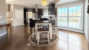 A spacious kitchen with a large island, dark cabinetry, and a chandelier. - Spacious 4 bd Modern Home with Private Yard & Games (Woodbridge)