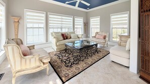 A spacious living room with a high ceiling, large windows, and a ceiling fan. - Spacious 4 bd Modern Home with Private Yard & Games (Woodbridge)