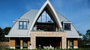 A modern house with a triangular roof, large windows, and a balcony. - Country Holiday Home for 6 Guests (Den Burg)