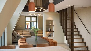 A modern interior with a dining area, sofas, a staircase, and pendant lighting. - Country Holiday Home for 6 Guests (Den Burg)