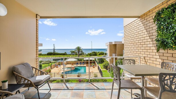 A balcony with a pool, chairs, and a table. - Look at the beach, Alexandra Headland, sleeps 5 (Alexandra Headland)