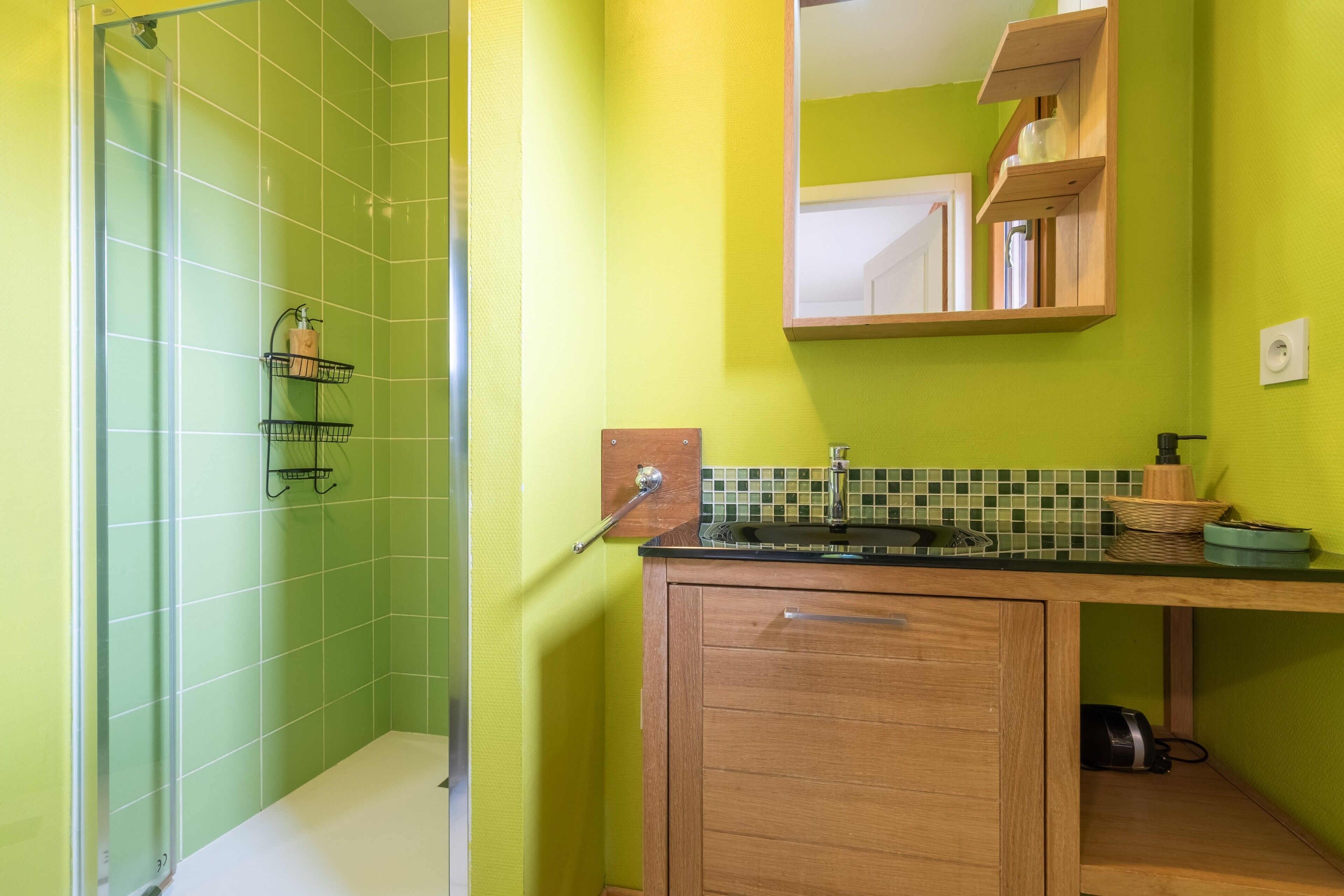 Une salle de bain avec une douche, un lavabo avec un miroir au-dessus et un meuble en bois en dessous.