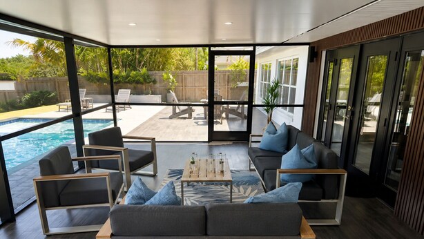 Ein modernes Wohnzimmer mit Pool, großen Fenstern und Blick auf den Garten.