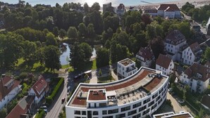 A modern building with a curved roof, surrounded by traditional houses and a body of water. - 4 Star Holiday Home in Travemunde (Lübeck)