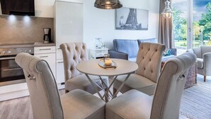 A modern kitchen with a dining area, a sofa, and a large window with a view. - 4 Star Holiday Home in Travemunde (Lübeck)
