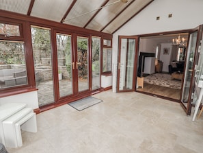 A room with a large sliding glass door leading to a patio, a white table with benches, and a fireplace. - Willows Lodge at Carreg Llwyd (Cardiff)