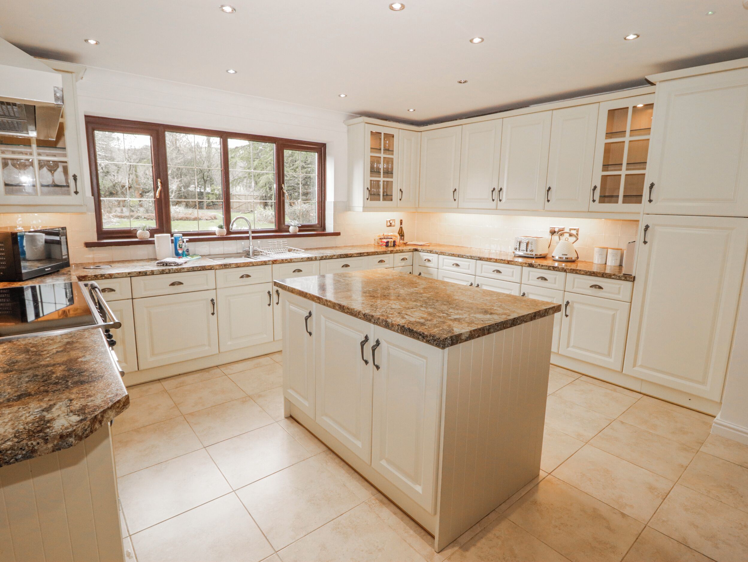 A spacious kitchen with white cabinets, granite countertops, and a large island.