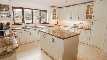 A spacious kitchen with white cabinets, granite countertops, and a large island.