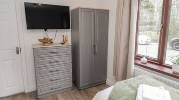 A bedroom with a bed, a wardrobe, a television, and a window with a view of the outside.
