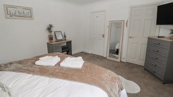 Un dormitorio con cama, cómoda, escritorio y espejo.
