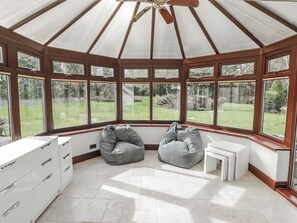 A conservatory with a wooden ceiling, large windows, and a seating area with bean bags. - Willows Lodge at Carreg Llwyd (Cardiff)