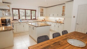 Una cocina amplia con armarios blancos, una mesa de comedor de madera y un ventanal grande.