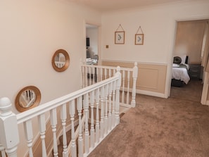 A hallway with a white railing, a mirror, and framed artwork on the wall. - Willows Lodge at Carreg Llwyd (Cardiff)