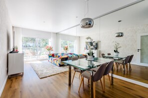 A modern living room with a glass dining table, a colorful sofa, and a large window. - Forte Beach Retreat (350m to the Sea) (Albufeira)