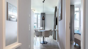 A modern hotel room with a dining area, a ceiling fan, and large windows. - 4 Star Holiday Home in Travemunde (Lübeck)