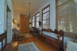 Ein Zimmer mit Holzbänken, einem gemusterten Teppich und einem großen Fenster mit Jalousien.