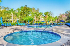 A hot tub surrounded by lounge chairs and umbrellas, with a pool in the background. - Magic stay near Disney (Davenport)
