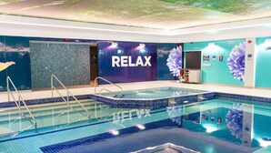 A swimming pool with a 'RELAX' sign, a tiled floor, and a wall with a floral mural. - Mayfly Lodge (Bodmin)