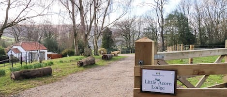 Un sendero de grava que conduce a una puerta de madera con un letrero que dice Little Acorn Lodge.