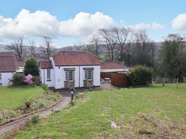 A white house with a red-tiled roof, a garden with a path, and a fenced yard. - Little Acorn (Whitby)