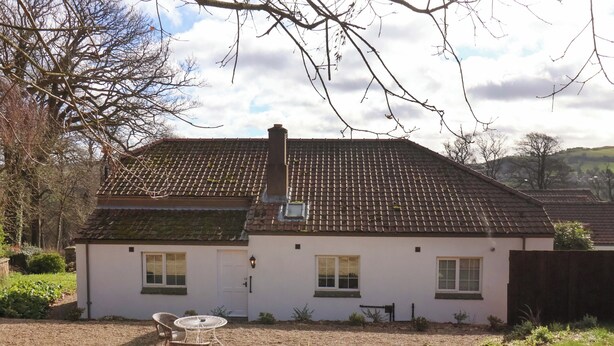 A two-story house with a tiled roof, a chimney, and a small garden with a table and chairs. - Hawthorn Lodge (Whitby)