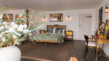 A bedroom with a bed, bedside tables, a nightstand, a chair, a dresser, a mirror, and a potted plant.