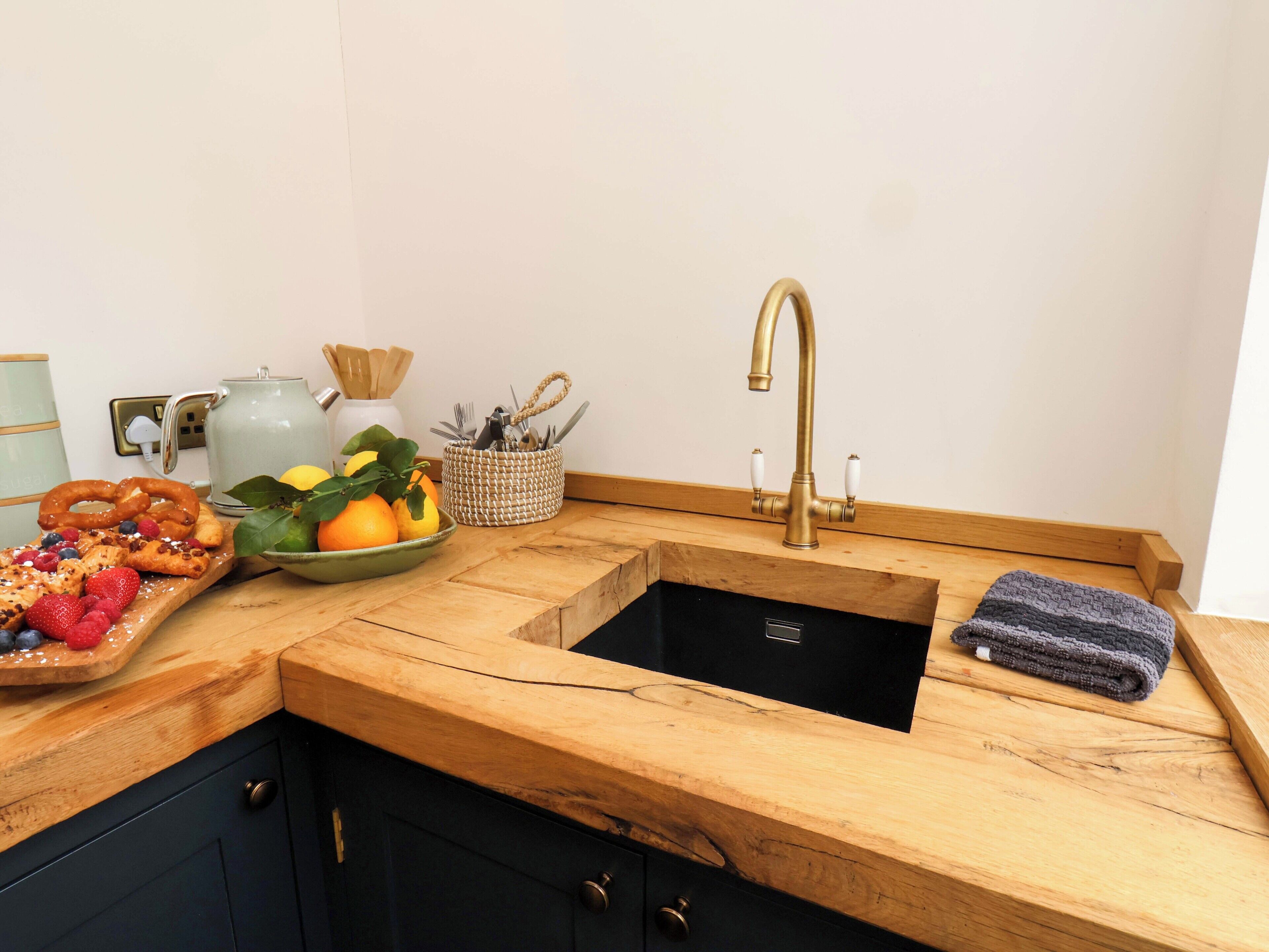 A kitchen with a wooden countertop, a sink, and a fruit bowl.