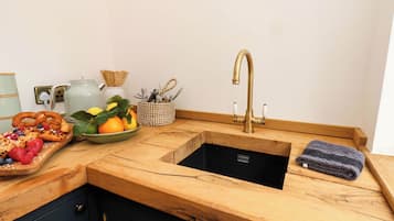 A kitchen with a wooden countertop, a sink, and a fruit bowl.
