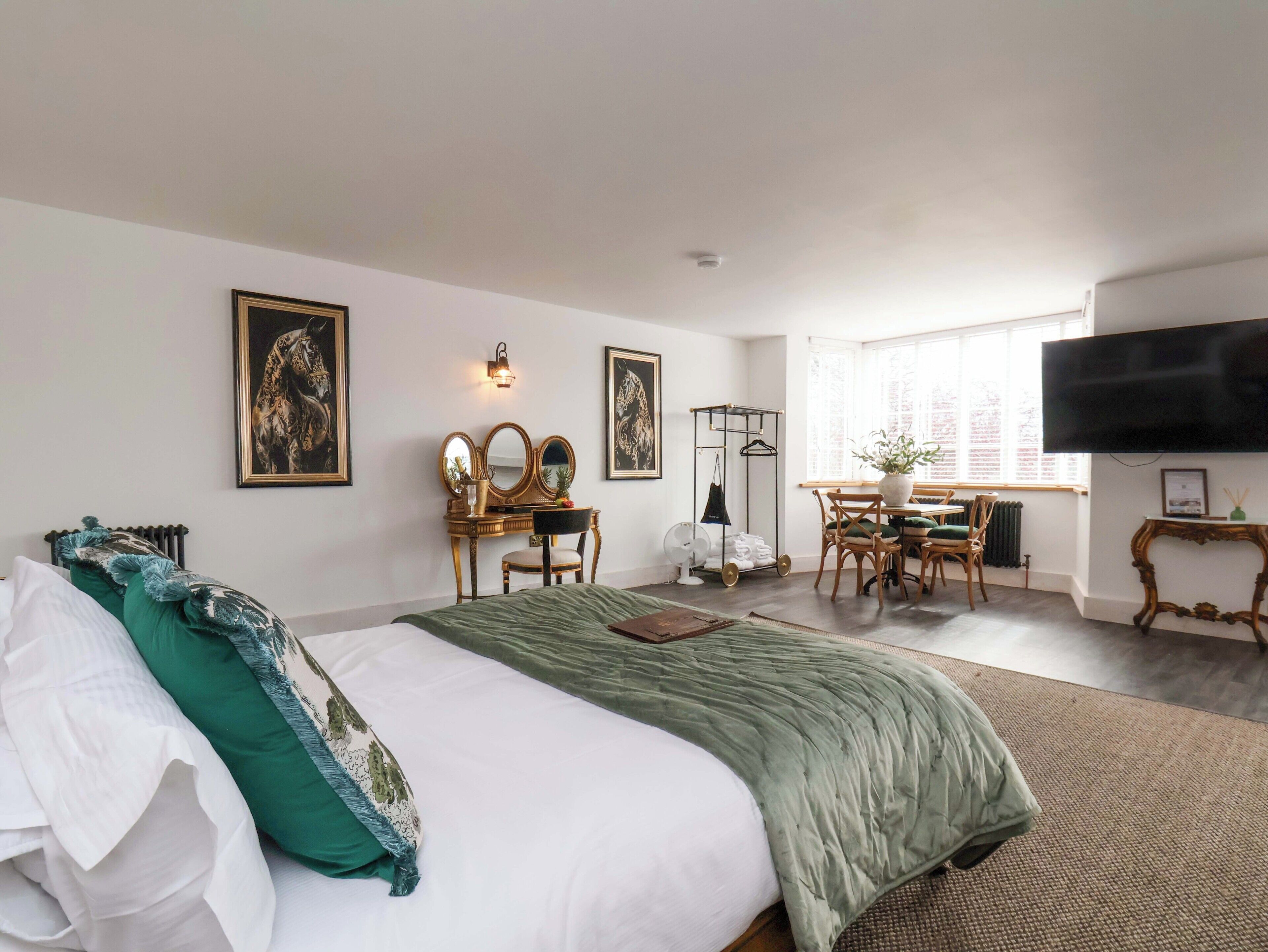 A hotel room with a bed, a desk, a chair, a television, and artwork on the walls.