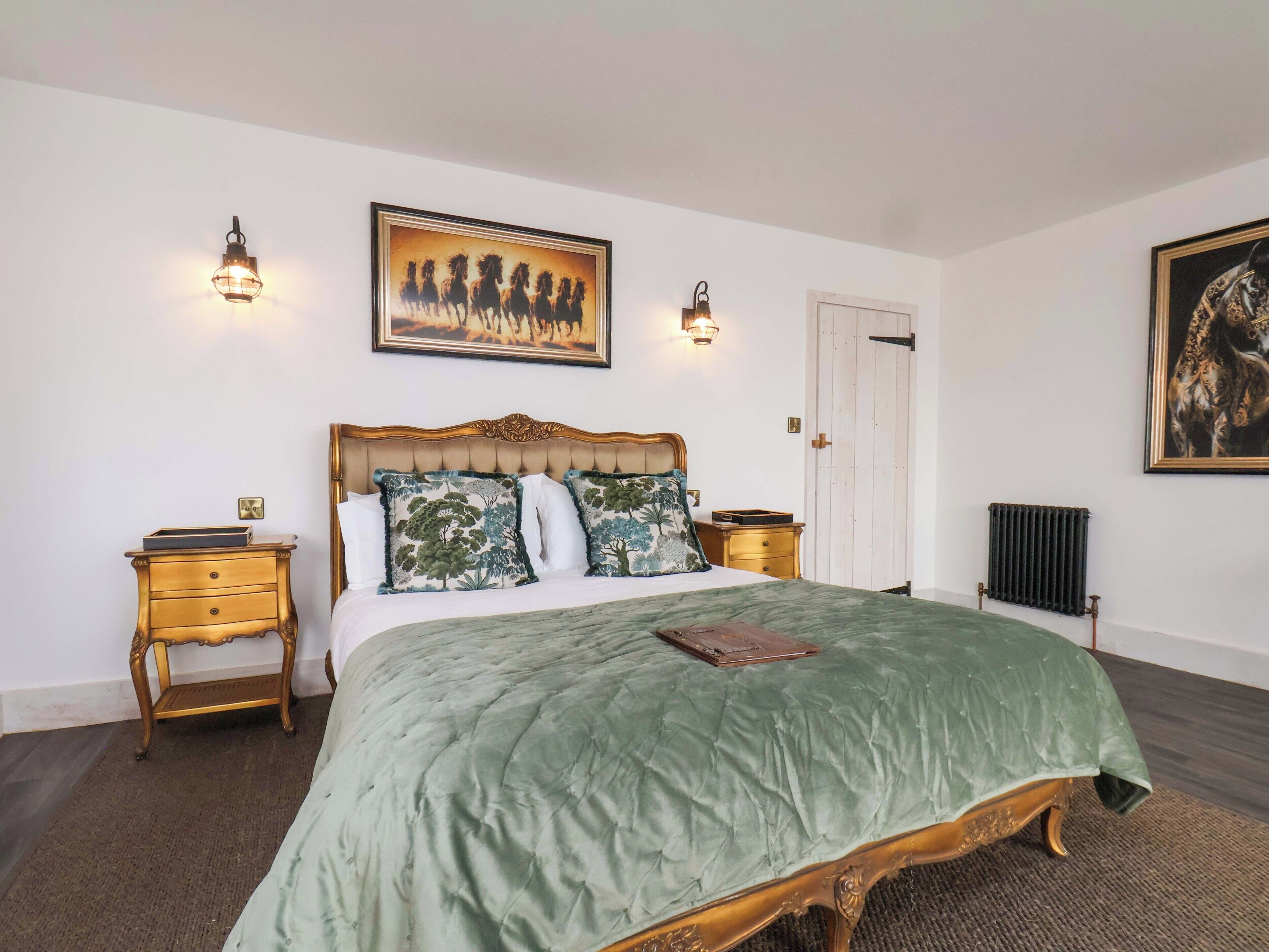 Une chambre à coucher avec un grand lit, deux tables de chevet, un radiateur et deux lampes fixées au mur.
