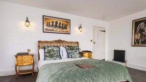 A bedroom with a large bed, two bedside tables, a radiator, and two wall-mounted lights. - Hawthorn Lodge (Whitby)