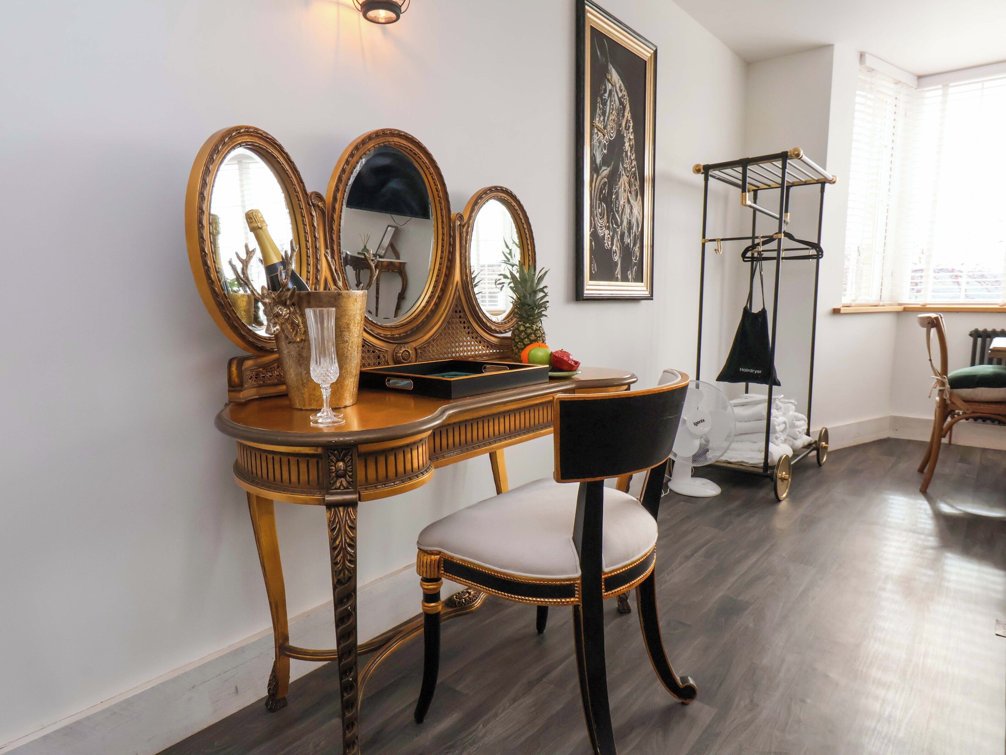 A vanity with ornate mirrors, a glass vase, and a fruit bowl.