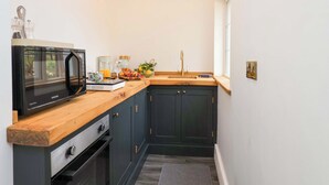 A compact kitchen with a microwave, sink, and wooden countertop. - Hawthorn Lodge (Whitby)