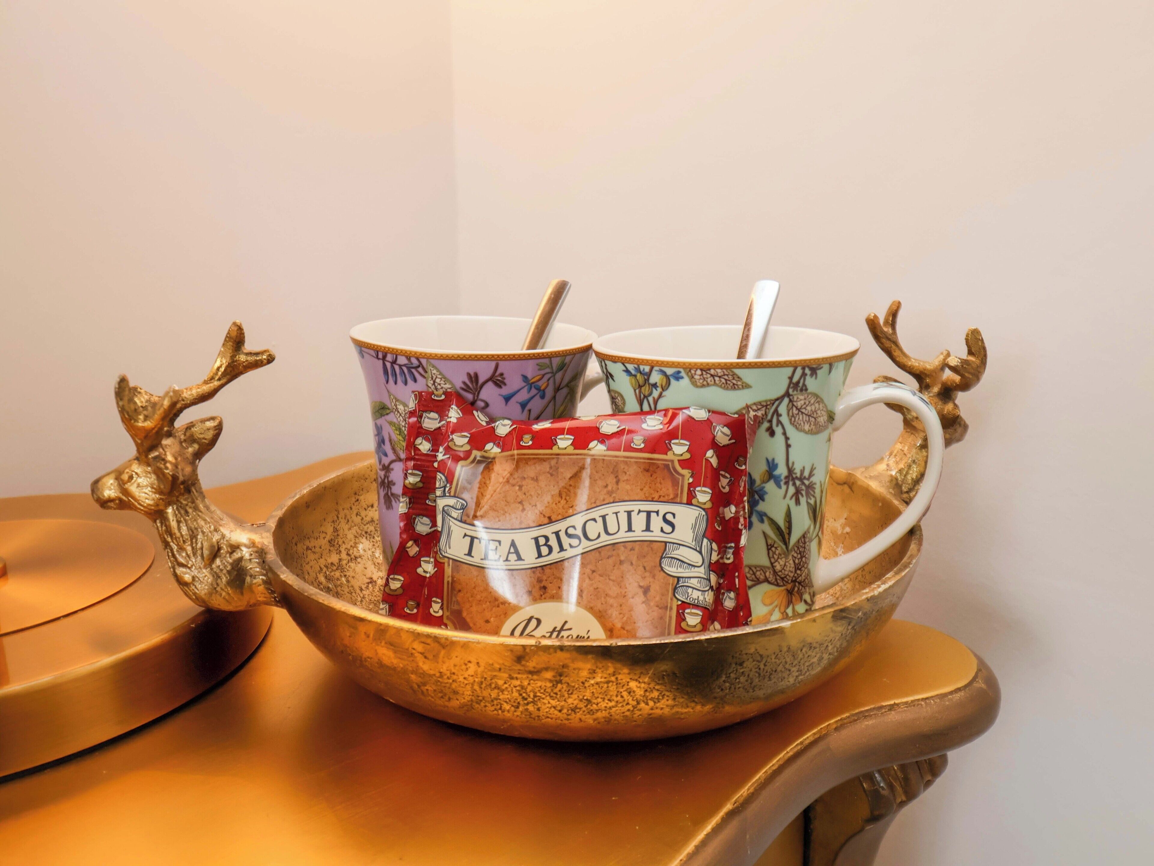 A tray with two ceramic mugs and a tea biscuit packet.
