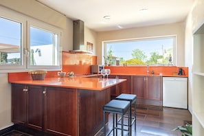 A modern kitchen with a large island, wooden cabinets, and a view through the windows. - Casa Alba, 4 km from the beaches Empúries (Albons)