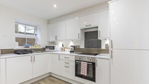 A modern kitchen with white cabinets, a built-in oven, and a window with a view. - Amy`s House - close to the Peak District! (Alton Towers & Staffordshire Villages)
