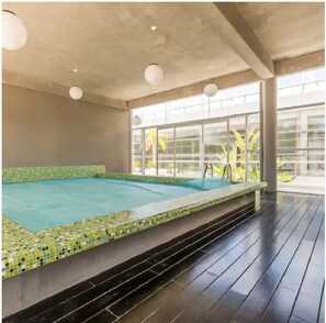 An indoor swimming pool with a tiled edge, a wooden deck, and large windows allowing natural light. - MODERNO, COMODO & SEGURO vive Punta Día & Noche!! (Punta del Este)
