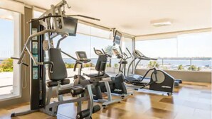Une salle de sport équipée de machines de cardio et de matériel de musculation, dotée de grandes fenêtres et offrant une vue sur l’extérieur.