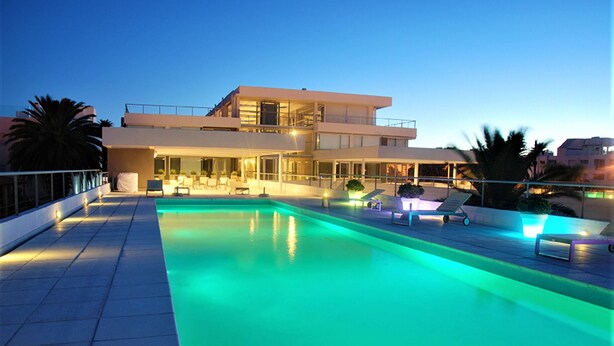 Un hôtel moderne doté d’une piscine sur le toit, d’un espace extérieur aménagé et d’une structure à deux étages.