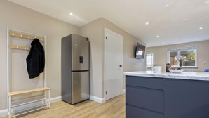 Une cuisine moderne dotée d’un réfrigérateur encastré, d’un plan de travail blanc et d’un banc en bois.